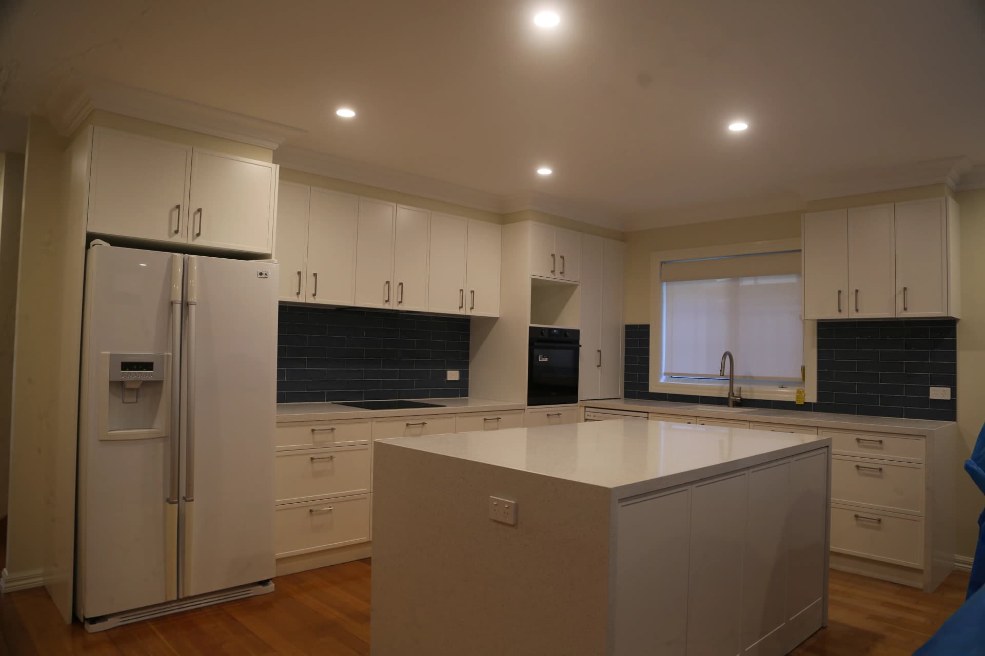 Modern kitchen renovation with white shaker cabinetry, blue subway tile splashback and island bench in Glenroy